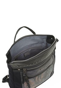 Bolso de tela negra y cuero con cierre superior con cremallera, múltiples bolsillos y tachuelas; el interior tiene un forro suave en gris y un bolsillo adicional con cremallera.