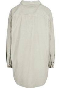 Chemise en velours côtelé gris clair avec une couture d'empiècement au dos, manches longues et poignets boutonnés. Présente une texture nervurée verticale et un ourlet légèrement incurvé.