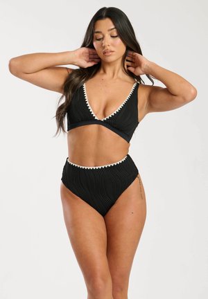 Zwart bikini set met een geribbeld textuur en witte golvende details. De top heeft een V-hals ontwerp en de onderkant is hoog in de taille.
