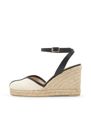 Keil-Espadrille mit beiger Canvas-Kappe, schwarzem Lederknöchelriemen mit goldener Schnalle und geflochtener Jute-Plateausohle.