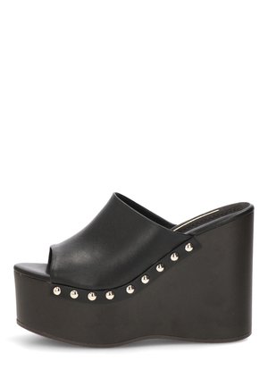Mule de cuña negra con punta abierta y tachuelas plateadas a lo largo del lateral del tacón de plataforma.