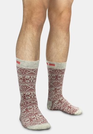 Kniestrümpfe in Beige mit einem roten geometrischen Muster. Rippbund, weiche Textur und verstärkte Spitze in passender Farbe.