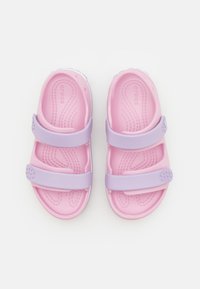 Rosa och lavendelfärgade träskor med två justerbara remmar, texturerad sula och cirkulär detalj på remmen. Lätta och bekväma att bära.