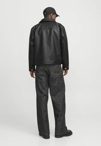 Black leather jacket with a wide collar, paired with loose-fitting dark denim jeans. Notable details include button accents and a smooth texture.