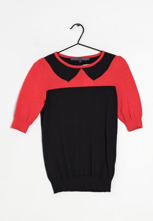 Czarna sukienka na krótki rękaw z czerwonymi bufkami na rękawach i czerwonym, zaokrąglonym kołnierzykiem, zawieszona na czarnym wieszaku na białym tle.