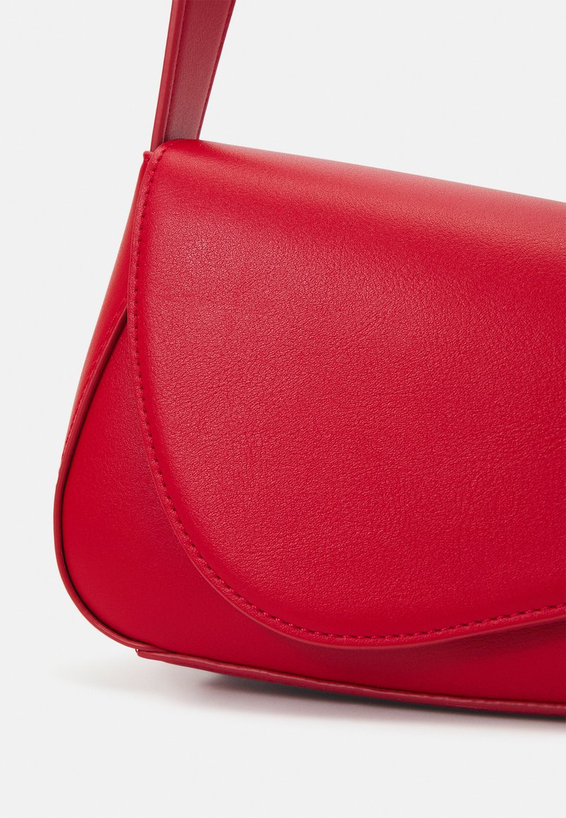 Borsa a mano in pelle rossa con una superficie liscia, chiusura con pattina arrotondata e dettagli di cucitura sottili. Design compatto e snello.