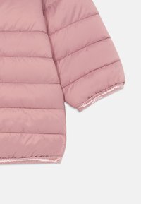 Manica di giacca imbottita rosa con motivo a quadri orizzontali, texture liscia e bordatura argento scintillante all'orlo.