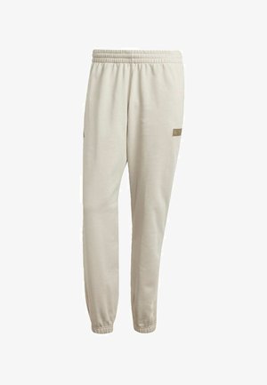 Pantalones de chándal beige claro con cinturilla elástica, puños ajustados y una pequeña etiqueta de marca cerca de la cadera. Tejido suave con una textura lisa.