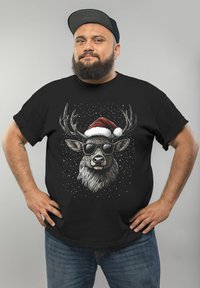 Black t-shirt featuring a graphic of a stag wearing sunglasses and a Santa hat, with a snowy background and intricate antlers.