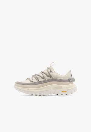 Beige und hellgrauer Sneaker mit dicker, strukturierter Sohle, gepolstertem Knöchelkragen, Zugschlaufe und einzigartigem Schnürsystem.