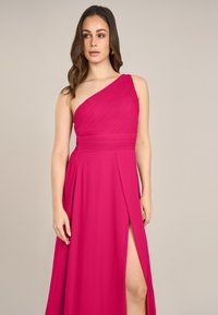 Ein schulterfreies rosa Kleid mit plissierter Textur, Seitenschlitz und tailliertem Schnitt. Hergestellt aus fließendem Stoff für eine glatte, elegante Silhouette.