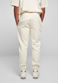 Joggers de color crema con un ajuste relajado, que cuentan con bolsillos laterales y un único bolsillo trasero, hechos de una suave tela texturizada.