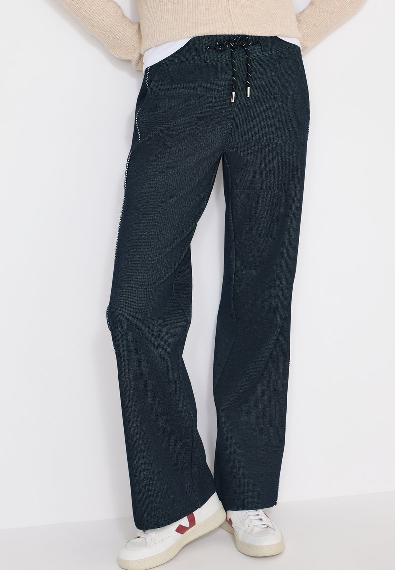 Pantalon bleu foncé à jambes larges en tissu texturé avec une taille élastique et un cordon de serrage ; doté de poches zippées latérales et de surpiqûres contrastées.