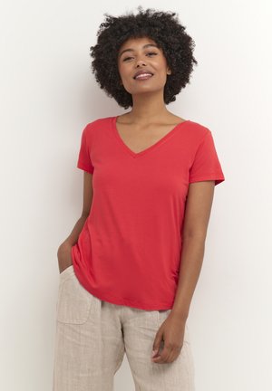 T-shirt rouge à col en V en tissu doux et lisse avec des manches courtes, accompagnée d'un pantalon léger et ample.