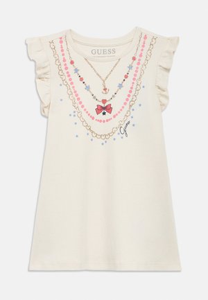 Kreminės spalvos suknelė be rankovių, su raukiniais ant pečių, pažaisdinta rožiniais ir auksiniais vėrinių raštais, mėlynomis žvaigždėmis, raudona kaspino aplikacija ir „Guess“ logotipu priekyje.