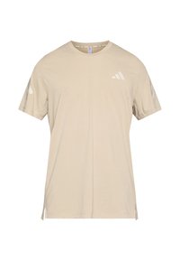 Camiseta beige de manga corta hecha de tejido suave. Presenta un logo blanco en el pecho y detalles angulados en las mangas. Bajo recto con aberturas laterales.