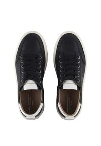 Coppia di sneakers nere basse con suole bianche e dettagli sul tallone, lacci neri e solette con marchio, su sfondo bianco.