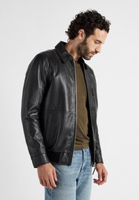 Schwarze Lederjacke mit glatter Textur, Reißverschluss und Seitentaschen. Rippbündchen und Saum, mit klassischem Kragen-Design.