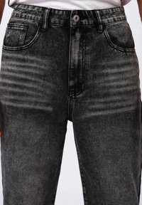Sorte denim jeans med en falmet design, med høy midje, frontlommer og synlige sømdetaljer. Glatt tekstur, rett passform.
