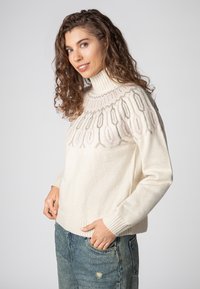 Cremefarbener Pullover mit einem hohen Rippkragen, der ein florales Muster in sanften Rosa- und Grautönen rund um die Passe aufweist. Strukturiertes Gewebe, lässige Passform.