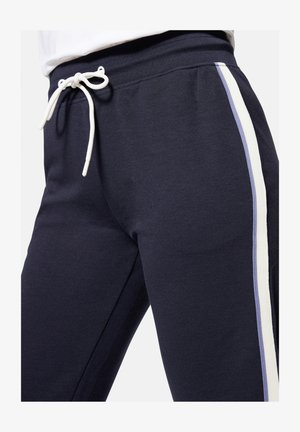 Navy sweatpants feature a drawstring waistband, side stripes in white and light blue, and textured fabric for comfort.