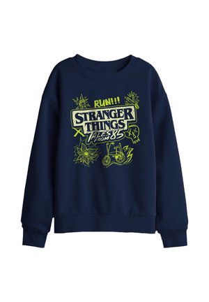 Marineblaues Sweatshirt mit neongelbem Schriftzug „Stranger Things Tales from 85“, Fahrrad-, Blumen-, Totenkopf- und Blitzgrafiken auf der Vorderseite.