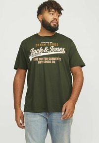 Tume roheline puuvillane T-särk, millel on valge ja oranž tekst brändinimega "Jack & Jones", ümmargune kaelus, lühikesed varrukad, vabalt lõigatud, igaühe jaoks sobiv disain.