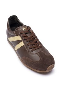 Hnedá kožená a semišová teniska s béžovými bočnými pruhmi, hnedej šnúrky a zvrásnenou podrážkou, naklonená tak, aby ukázala predné a bočné detaily.