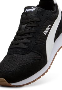 Fekete sportcipő hálós és velúr anyagból, fehér oldalsávval és fekete fűzővel. A gumitalp texturált felületű.