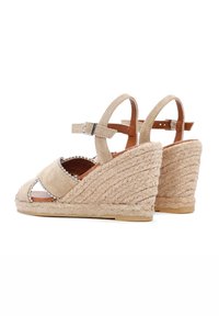 Beige suède wedge sandalen met geweven touwhakken, open teen ontwerp, verstelbare enkelsluiting en decoratieve parelaccenten.