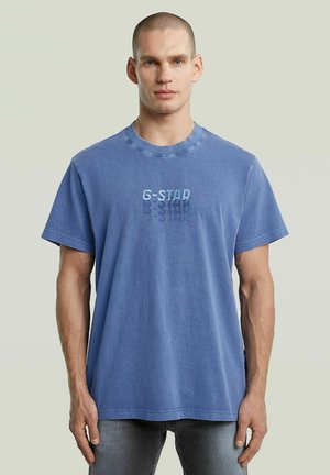 T-shirt en coton bleu avec des manches courtes et un col rond, arborant un logo G-Star subtil en bleu plus foncé au centre.