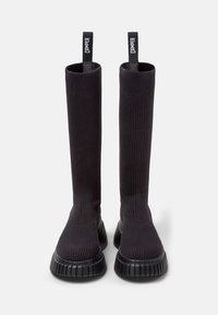 Botines negros de punto con textura acanalada, que cuentan con una suela gruesa de goma estriada y tiradores en los puños con la etiqueta "CAMPER".