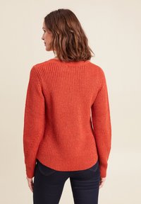 Maglione rosso lavorato a maglia con un motivo tessurato, scollatura rotonda e maniche lunghe, con un orlo leggermente curvo e polsini a costine.