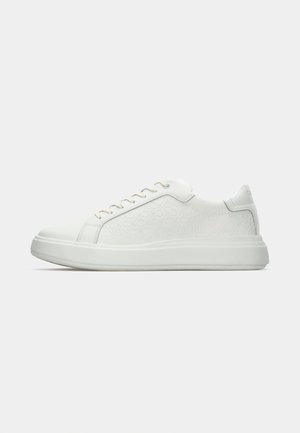 Baskets blanches avec un dessus en cuir texturé arborant un motif logo répétitif, un bout rond et une semelle en caoutchouc offrant une légère augmentation de hauteur.