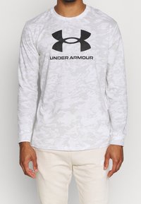 Langärmliges graues Camouflage-Shirt aus leichtem Stoff, mit einem auffälligen schwarzen Under Armour-Logo auf der Brust.