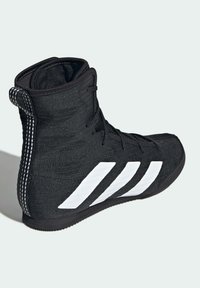 Musta painikenkä, jossa on tyylikäs kangaspäällinen, kolme valkoista vinoviivaa ja kuvioitu musta pohja. Korkea nilkkamalli ja vetolenkki.