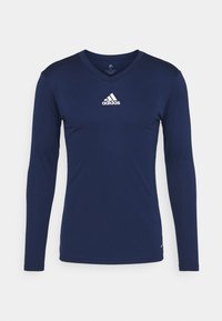 Laivastonsininen pitkähihainen paita V-kaula-aukolla, jossa on valkoinen Adidas-logo rinnassa. Valmistettu sileästä ja hengittävästä kankaat.