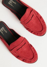 Røde ruskind slip-on loafers med pyntede kanter, der har et syet mønster og en lille dekorativ udsparing på overdelen. Sort indersål.