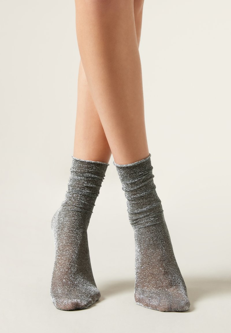Sparkly silver ankle socks with a ruched design, showcasing a soft texture and a shimmering finish. Visible toe area without patterns.