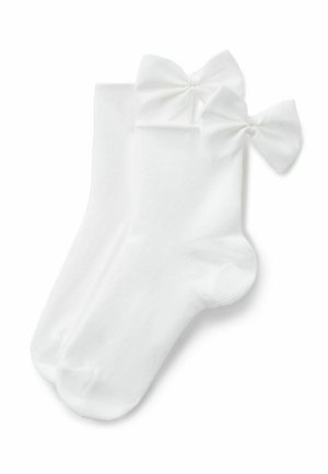 Białe skarpetki do kostek z dużymi kokardami wykonanymi z tkaniny przyszytymi blisko górnej krawędzi, prezentowane na płasko na białym tle.