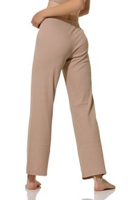 Pantalons larges beige à côtes avec une taille élastique, présentant une texture lisse et une coupe décontractée, affichés de profil.