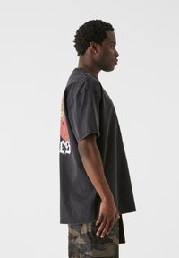 Sort oversized t-shirt med grafisk print på ryggen. Fremstillet af bomuld, med korte ærmer og lige snit.