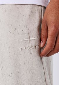 Lichtgrijze atletische broek van textuurstof, met een subtiele spikkelpateren en een geborduurd logo aan de zijkant.