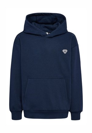 Lyshåret dreng iført navyblå hættetrøje og joggingbukser med grønne sneakers, stående og vendt fremad på ensartet lysegrå baggrund.