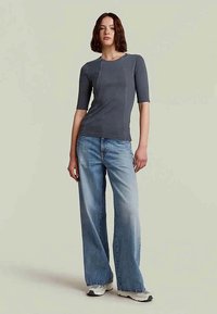 Grå ribbet topp med korte ermer, tettsittende design. Kombinert med lyseblå brede bukser. Strukturert stoff, uformell stil.