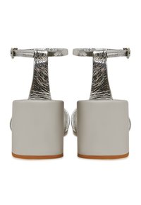 Tocuri groase cu barete argintii texturate și catarame la gleznă, prezentate din spate pe un fundal alb.