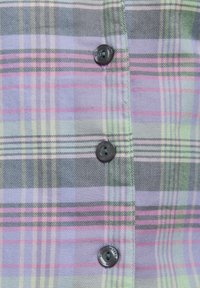 Plaid shirt featuring shades of purple, pink, and green. Button closure with black buttons and soft fabric texture. Light and casual design.