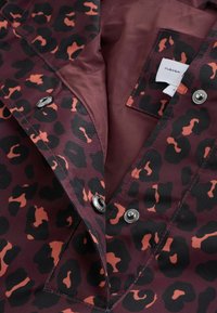 Tumepruun jope musta ja oranži leopardimustriga, metallist trukikinnitustega ning sise taskuga, millel on valge kangasilt.