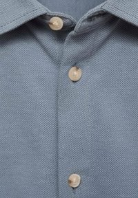 Light blue textured shirt featuring a button-down collar with beige buttons and visible stitching at the placket.