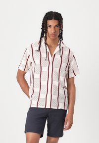 Korte mouw, button-up shirt in crème met maroon gestreepte patronen, met een textuurstof en een klassieke puntkraag. Gekocht met een donkere short.